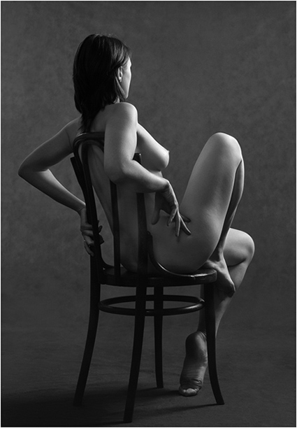 Полностью голая девушка позирует сидя в кресле